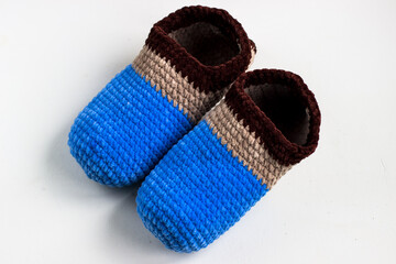 Knitted slippers in blue and brown colors. Plush yarn slippers on a white background
