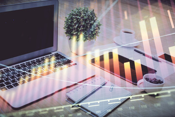 Stock market graph on background with desk and personal computer. Double exposure. Concept of financial analysis.