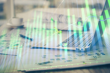 Stock market graph on background with desk and personal computer. Double exposure. Concept of financial analysis.