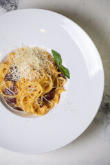 top view carbonara pasta with bacon, cream and cheese on a white plate in a restaurant