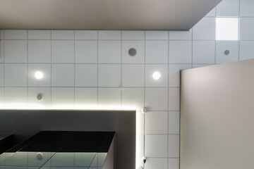 suspended ceiling with halogen spots lamps and drywall construction in empty room in apartment or house. Stretch ceiling white and complex shape.