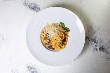 top view carbonara pasta with bacon, cream and cheese on a white plate in a restaurant