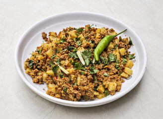 Aloo qeema or potato keema served in plate isolated on table top view of indian and pakistani spicy food