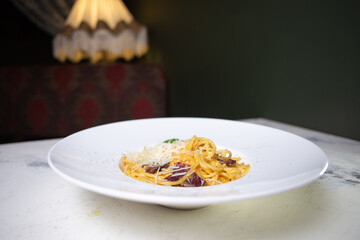 pasta with bacon and cheese on a white plate in a restaurant