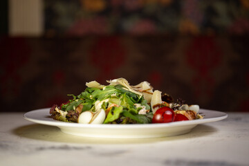 Salad with shrimp and tomatoes, cheese and herbs on a plate in a restaurant