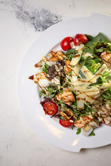 top view salad with shrimp and tomatoes, cheese and herbs on a plate in a restaurant