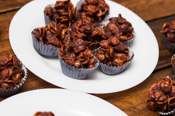 Chocolate cornflake cookies served on white plates. Chocolate cornflake cake in blue paper cupcake case
