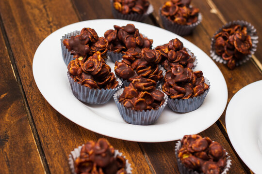 Chocolate cornflake cookies served on white plates. Chocolate cornflake cake in blue paper cupcake case