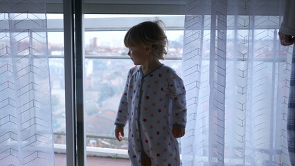 Baby toddler looking at automatic blinds going up, starting the day concept