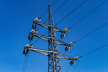 Mast of a high-voltage power line against the blue sky.