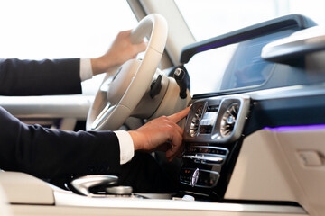 a man in a formal suit presses the start stop button in an expensive car