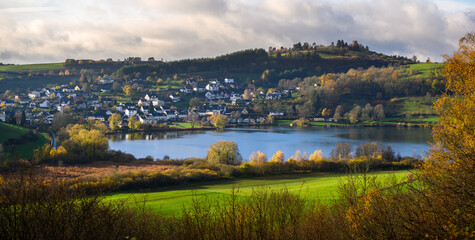 Fototapeta na wymiar Hillside town of Schalkenmehren with volcanic lake and observatory in fall