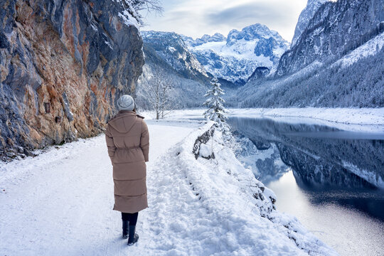 Beautiful snowy winter landscape with Dachstein mountain and Gosausee in Austria near Hallstatt with tourist woman