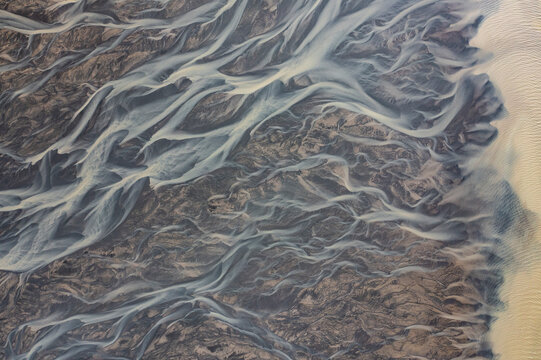Aerial view of abstract water formation from a river estuary at Holtsos lake along the coast, Iceland.