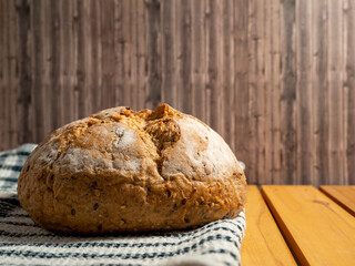 Dark bread on a wooden background. Round Bread with grains.