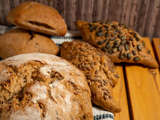 Dark bread and buns on a wooden background. Bakery products with grains.