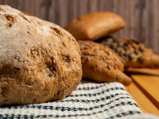 Dark bread and buns on a wooden background. Bakery products with grains.