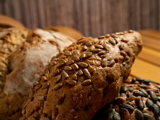 Dark bread and buns on a wooden background. Bakery products with grains.