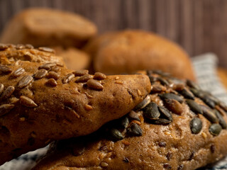 Dark buns on a wooden background. Bakery products with grains.