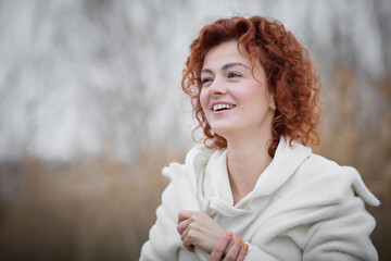 Close up portrait of attractive woman in trendy white coat poses in motion against the backdrop of an autumn landscape