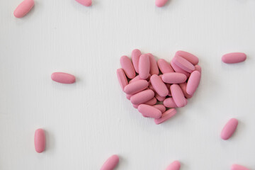 Pink Prenatal Vitamins in the shape of a heart, healthy pregnancy, motherhood concept, multivitamin pills, pink heart pills, pink heart vitamins on white background