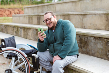 person in wheelchair using mobile phone and smiling in basketball court outdoor
