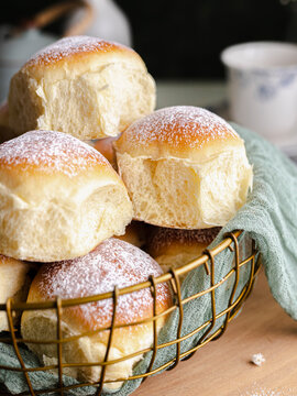 Homemade milk and creamcheese buns in a basket with a cloth next to a window