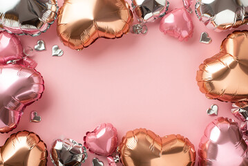 St Valentine's Day concept. Top view photo of heart shaped pink silver golden balloons and confetti on isolated pastel pink background with copyspace in the middle