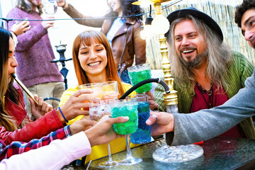 Group of trendy friends drinking and cheers cocktail at hookah bar restaurant party - Young...