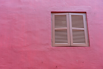Antique window with wooden shutters on a red wall in Chinatown, Singapore, copy space, closeup