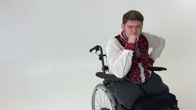 a young handsome on a wheelchair he sits on a white background there is a place for the text of experiencing suffering and also a lot of sadness we are invincible Glory to Ukraine Glory to the heroes