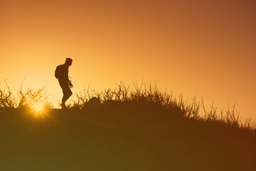 Obraz na płótnie Canvas Man silhouette hiking at sunrise 