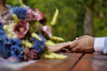 Couple Holding Hands Behind the Bride's Bouquet