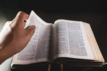 Leyendo la biblia, mano pasando de página, bendiciendo santa biblia y cruz de clavos en escritorio.