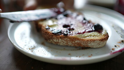 Close-up person spreading jelly on bread with butter