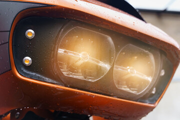 The included headlights of a motorcycle close-up, glowing yellow.