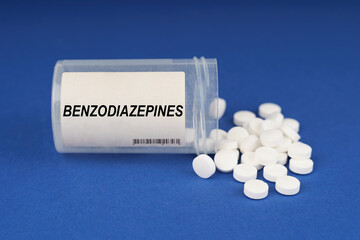 On a blue surface are pills and a dusty jar with the inscription - Benzodiazepines