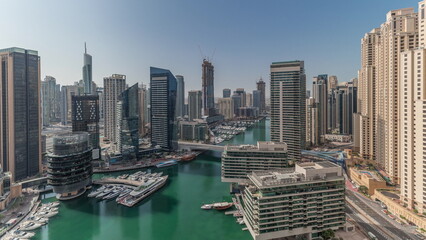 Naklejka premium Panorama showing aerial view to Dubai marina skyscrapers around canal with floating boats timelapse