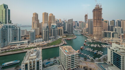 Fototapeta na wymiar Panorama showing Dubai Marina with several boat and yachts parked in harbor and skyscrapers around canal aerial timelapse.