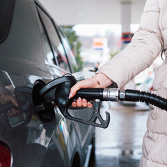 Woman pumping gasoline fuel in car at gas station. Petrol or gasoline price increase concept.