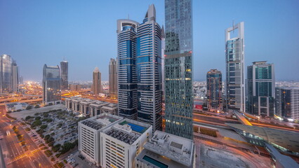 Aerial view of Dubai International Financial District with many skyscrapers night to day timelapse.