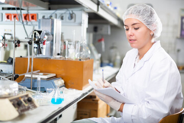 Attentive scientist engaged in research in chemical laboratory, noting results in test chart