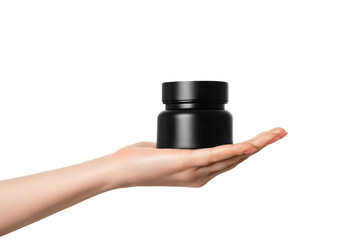 Black jar with a beautiful highlight in a female hand with a pink manicure, isolate.