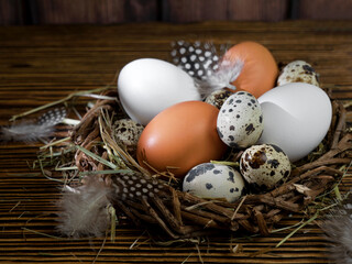 Easter eggs in a nest on a wooden background Greeting Easter card. Chicken and quail eggs