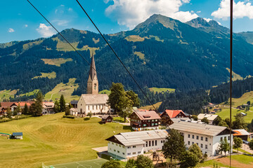 Fototapeta premium Beautiful aerial summer view of Mittelberg with a church, Kleinwalsertal valley, Vorarlberg, Austria