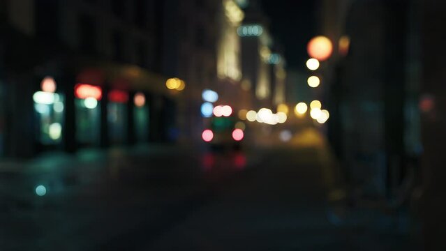 Ambulance is driving away in the defocused background with flashing emergency siren lights at night city