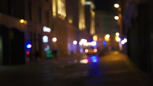 Blurry: Ambulance is driving away in the defocused background with flashing emergency siren lights at night city