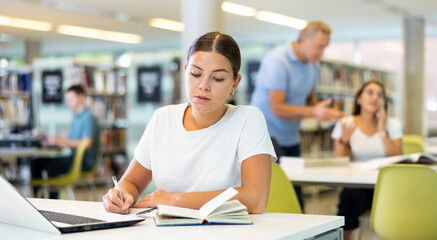 Fototapeta na wymiar Smart female American student preparing for the exam in the school library