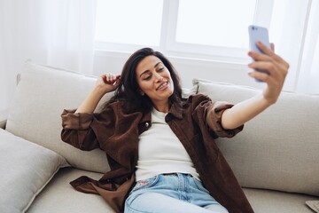 Woman blogger with phone lies at home on the couch and works freelancer online, selfie