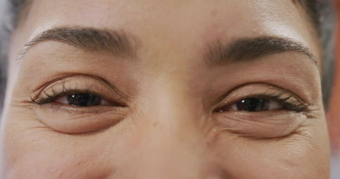 Close up portrait of eyes of happy biracial female doctor smiling and looking to camera